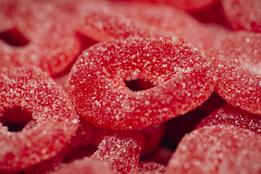 red gummies jelly candies in sugar, background.