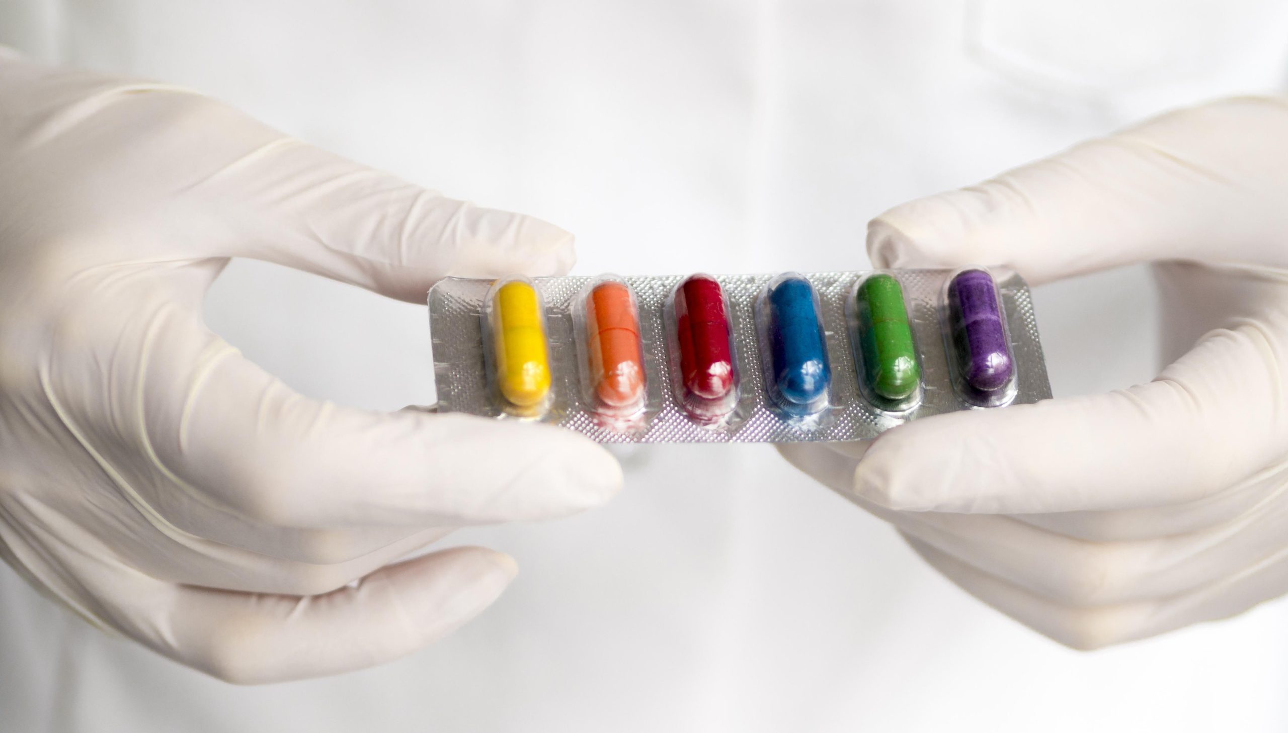 محصولات ما high angle doctor holding rainbow colored pills foil